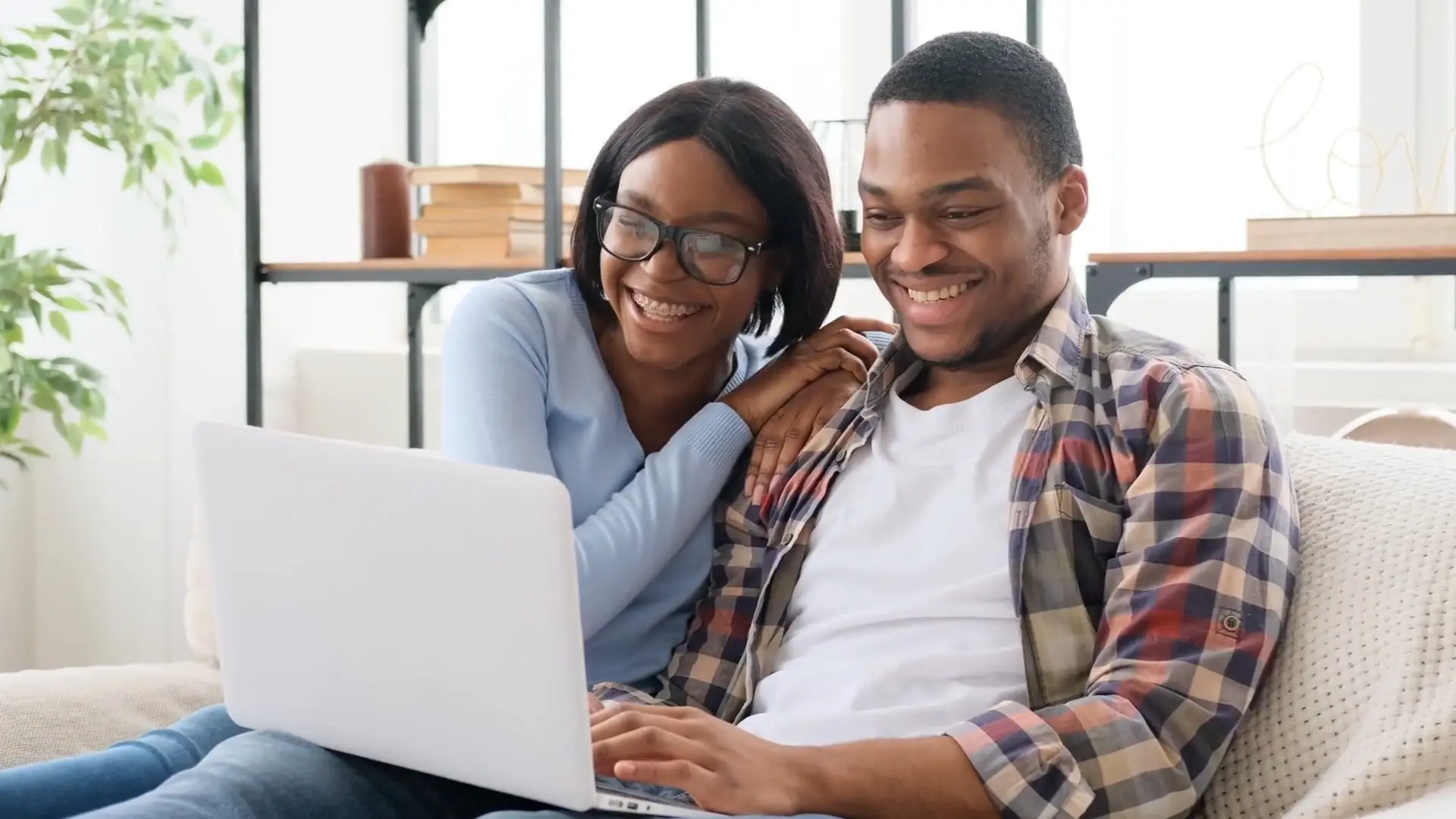 a young African American man and woman couple smiling and looking at a laptop doing a couples Kousouli Neural Emotive Reprogramming KNER session with Dr. Kousouli