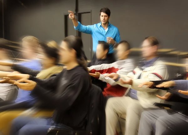 Dr. Kousouli hypnotizing a group of people seated in a room